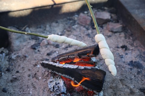 spett med pinnbröd över brasa